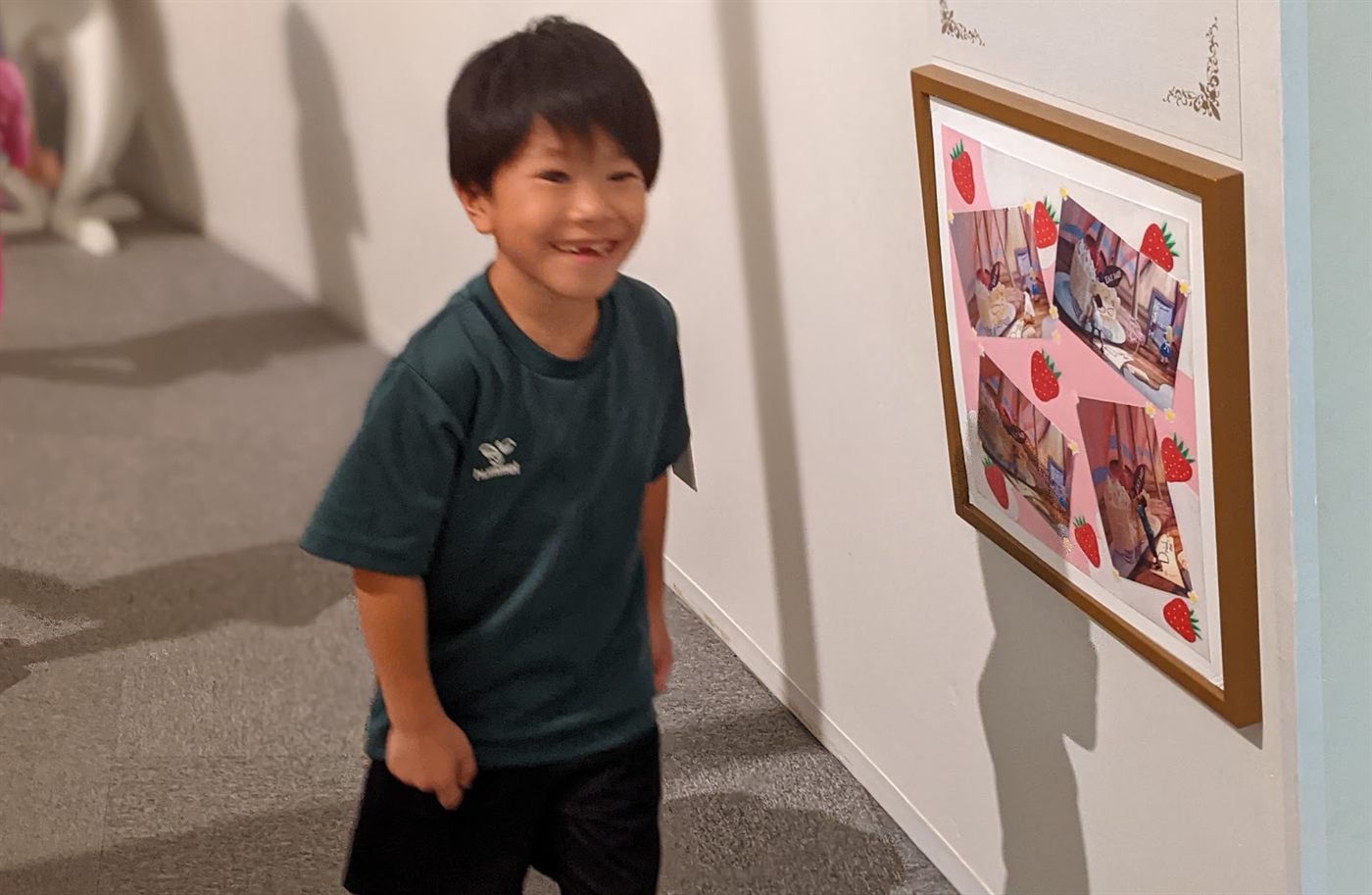 かべにかざられた作品をながめる男の子