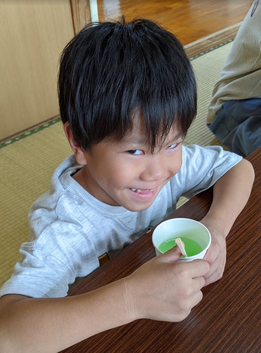 緑色のスライムを手に、満面の笑みを浮かべる男の子