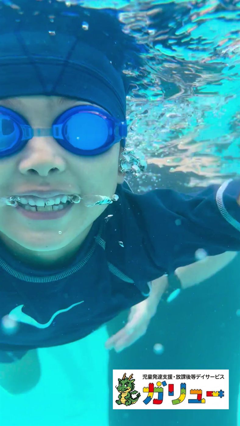 ゴーグルをつけて水中で笑顔を見せる男の子