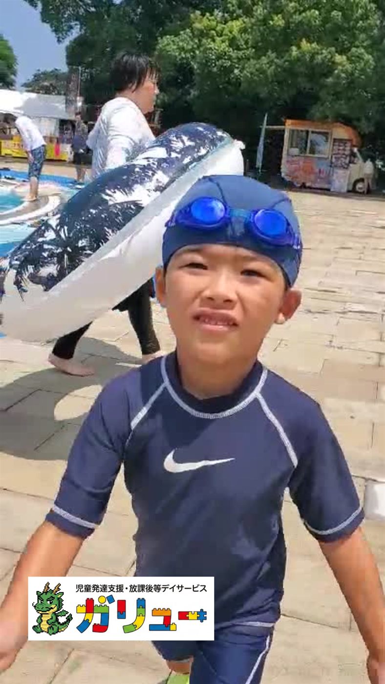 浮き輪を持ってプールサイドに立つ男の子