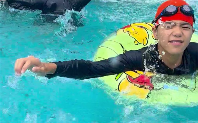 浮き輪につかまって笑顔を見せる男の子