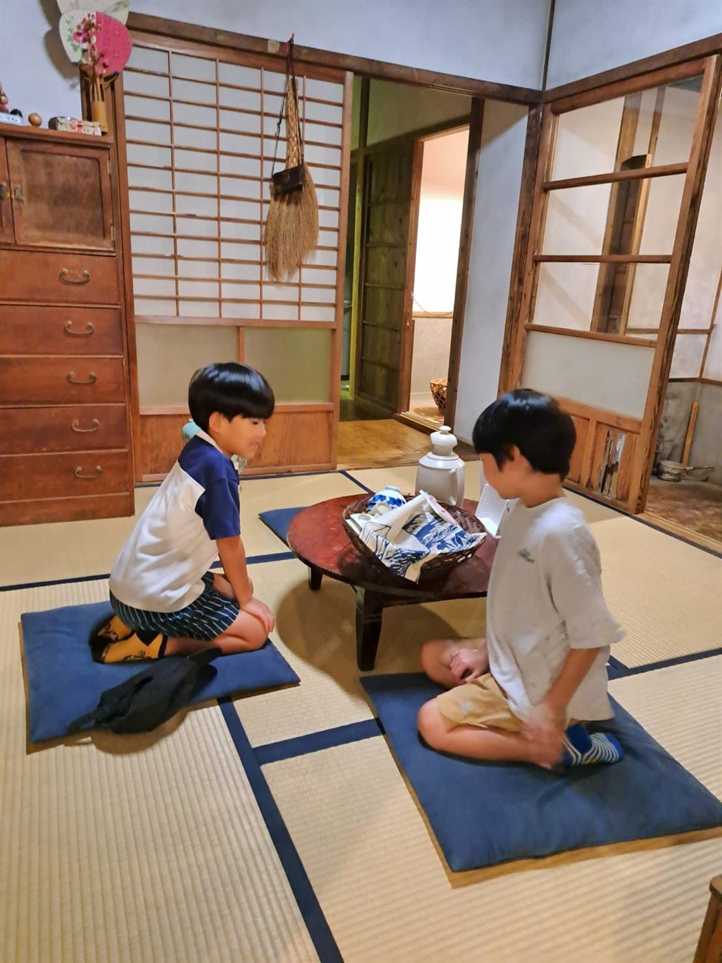 昔の家の座敷で、ちゃぶ台をはさんで正座する二人の男の子