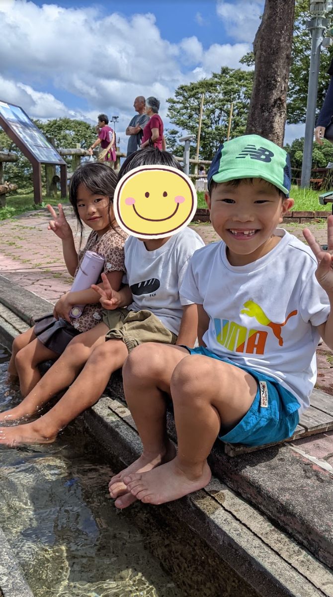 足湯に足をつけてピースサインをする子どもたち