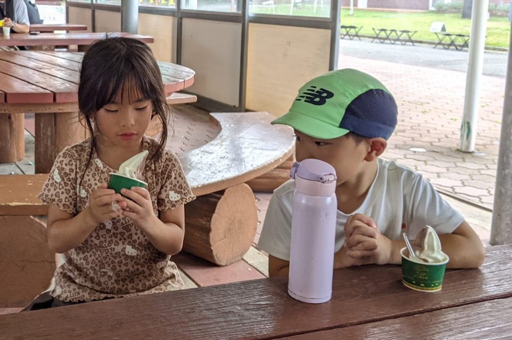 テーブルでソフトクリームを食べる二人の子ども