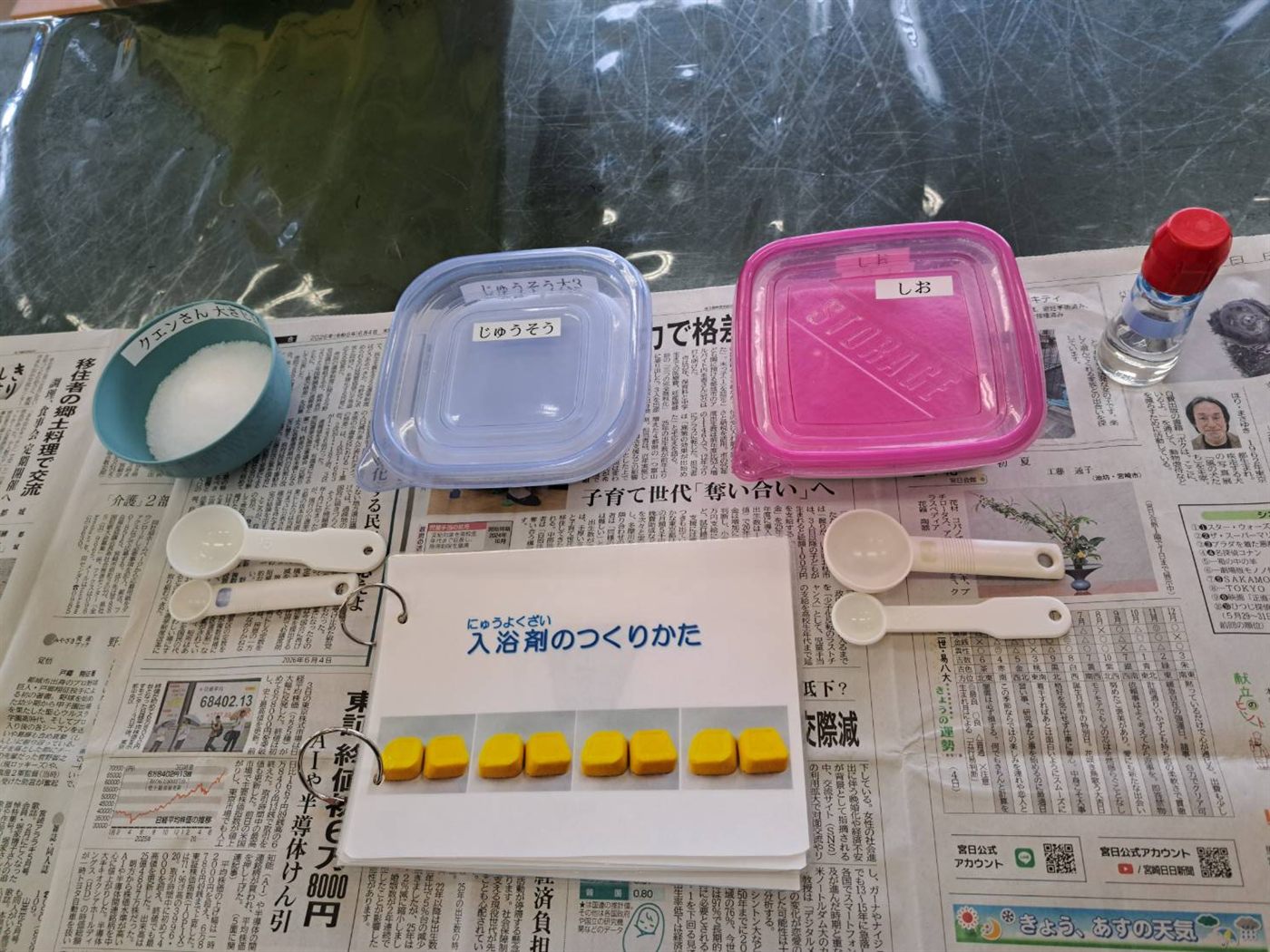 バスボム作りの材料。しお、じゅうそう、クエン酸と計量スプーン、作り方の説明パネル