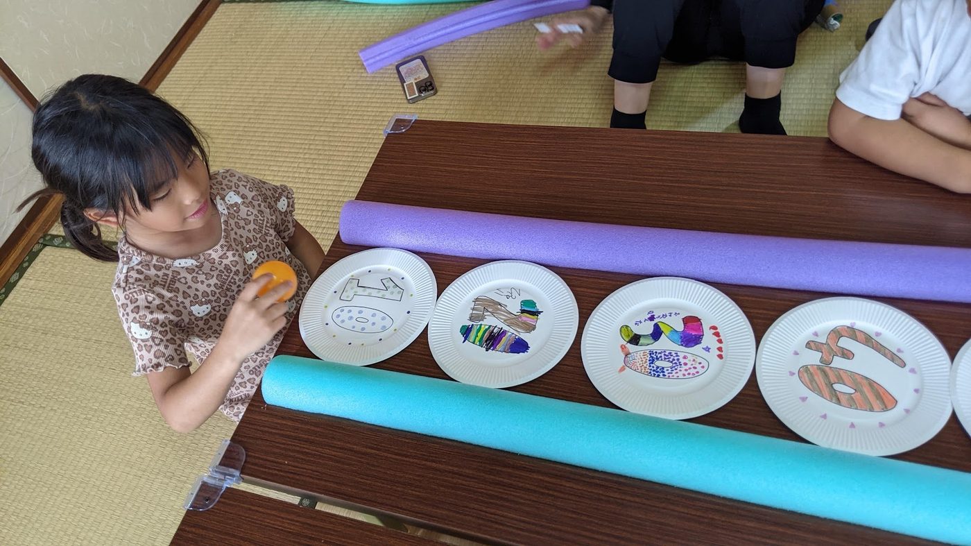 テーブルに並べられた、色とりどりの手作り点数板を見る女の子