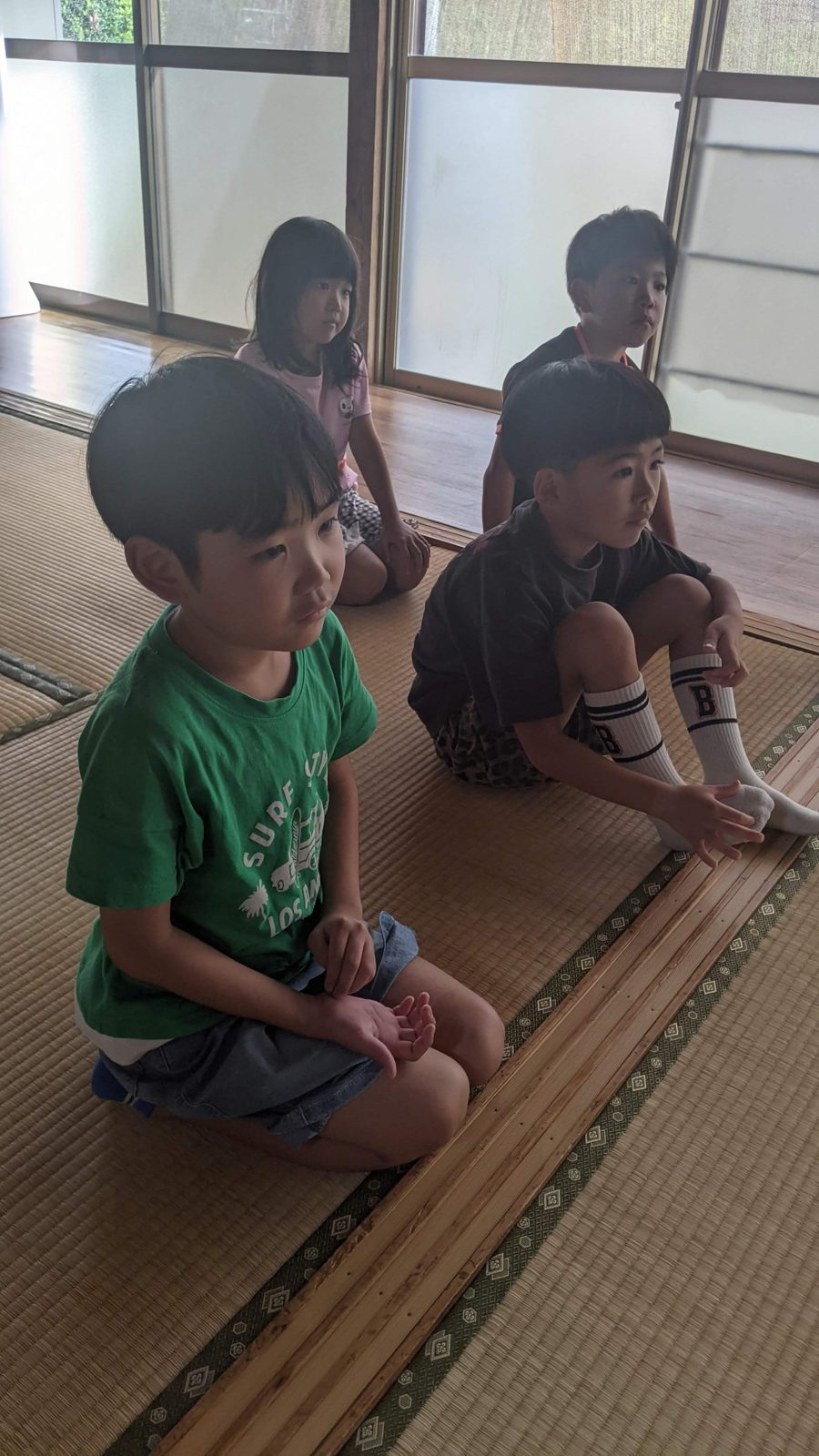 畳の部屋に座って、火災についての動画を静かに見る子どもたち